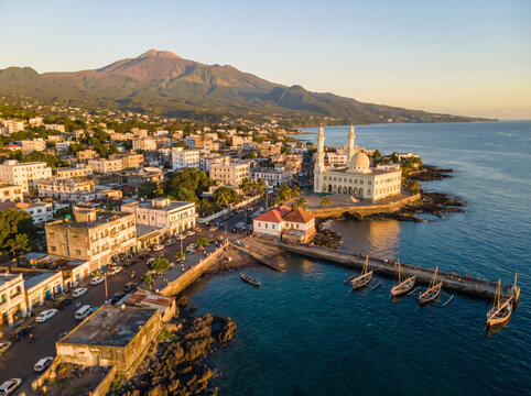 Aerial view of Moroni city with the Grand Mosque and Mount Karthala in the background at sunset.