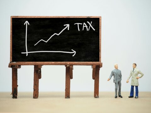 Mini toy of action figure at table with blur background. Business financial photography concept design. Minifigure of businessman character with 2026 growth graph at blackboard. Increase arrow chart.