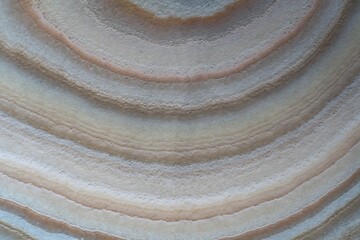 Naklejka premium Circular agate stone texture with concentric beige and grey bands and layered patterns