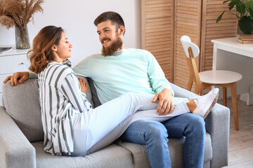 Fototapeta premium Happy couple in love sitting on sofa at home