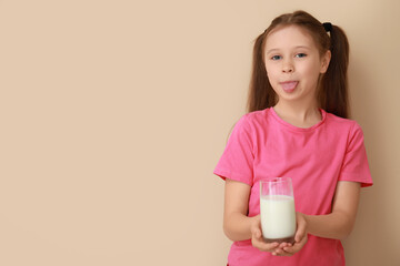 Funny little girl with glass of milk on beige background © Pixel-Shot