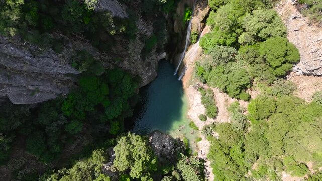 Top Down Drone View of Swimmers in Turquoise Natural Pool Below Polylimnio Waterfall in Rocky Canyon, Peloponnese Greece