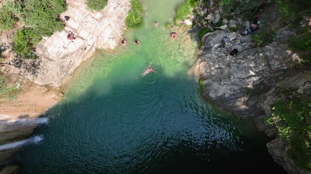 Aerial Top Down View of People Swimming in Turquoise Natural Pool Below Polylimnio Waterfall, Rocky Canyon in Peloponnese Greece