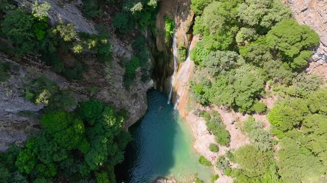 Aerial Drone View of Swimmers in Turquoise Pool Below Polylimnio Waterfall in Forest Canyon, Messinia, Greece