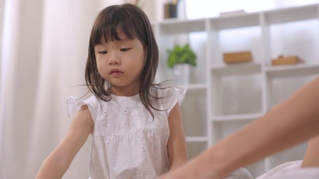 mother, daughter, family, Asian little girl touching ear with curious thinking expression at home, childhood learning moment, emotional quotient development, parenting lifestyle, cognitive behavior