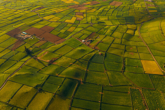 Aerial view of Pico Dona Joana geodesico and the patchwork of agricultural fields divided by stone walls under golden hour light in Feteira, Acores, Portugal.