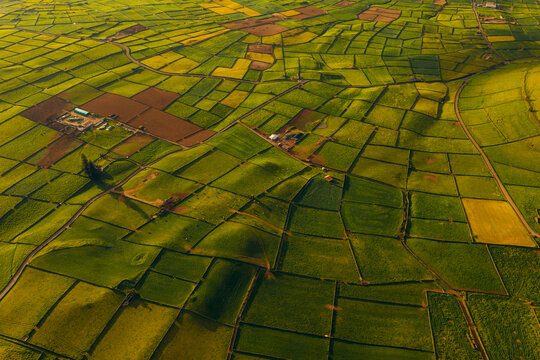 Aerial view of the lush green patchwork fields and stone walls of Pico Dona Joana geodesico under the warm golden light of sunset in Feteira, Acores, Portugal.