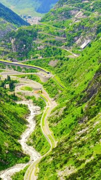 Vertical video. Switzerland. Gotthard Pass, the historic Tremola road with serpentine granite hairpins winding through the Schollenen Gorge, Drone footage with snow-capped peaks beyond. Drone footage