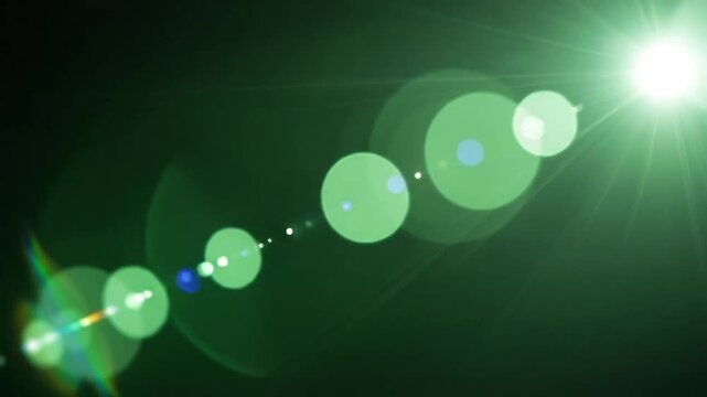 A bright green light source creates a lens flare effect on a dark background