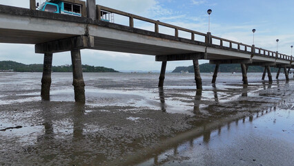 Fototapeta premium Low Angle View of a Concrete Pier Over Muddy Coastal Flats