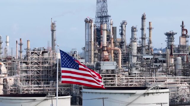 Industrial Phillips 66 Rodeo Renewable Energy Complex with large American flag waving in foreground under clear sky in San Francisco Bay Area, California. Aerial view. Patriotic state in USA.