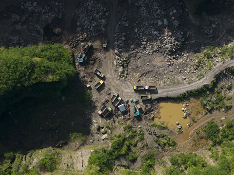 Aerial view of Tambang Pasir Merapi Kali Gendol Sand Mine with excavators loading trucks on a dirt road by rocky terrain Kecamatan Cangkringan, Daerah Istimewa Yogya, Indonesia.