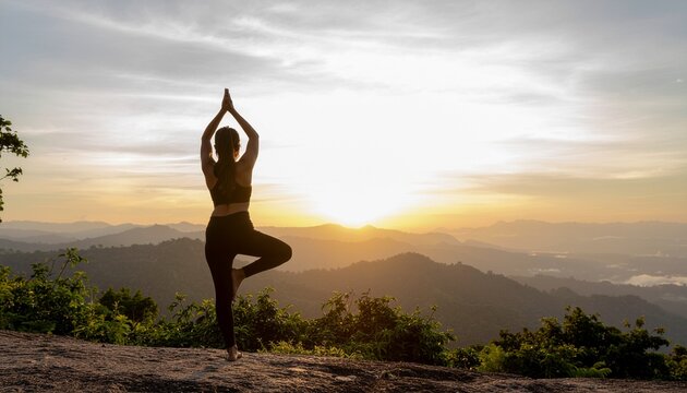 Serene mountain yoga session at sunrise, woman performing tree pose overlooking a valley, promoting wellness and mindfulness