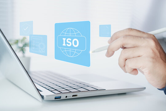 Business professional using laptop with ISO certified interface, quality assurance checklist, compliance verification, corporate standard, audit process, certification approval, security shield