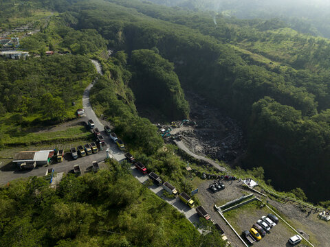 Aerial view of Tambang Pasir Merapi Kali Gendol Sand Mine with trucks on a road and excavators in a ravine in Kecamatan Cangkringan, Daerah Istimewa Yogyakarta, Indonesia.