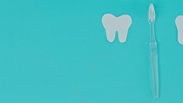 Minimalist Flat Lay With Large Left Copy Space Featuring Clear Toothbrush And Paper Tooth Cutout On Blue Surface