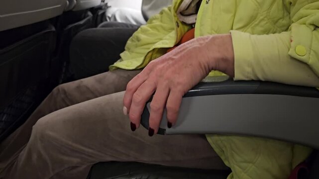 Woman hand resting on armrest in airplane during flight