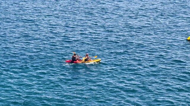 Two People Paddling a Yellow Tandem Kayak Across the Blue Mediterranean Sea