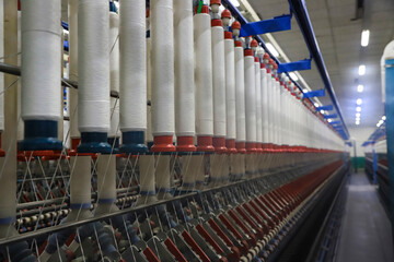 Fototapeta premium Close-up of White Yarn Cones on Spinning Machine in Textile Factory