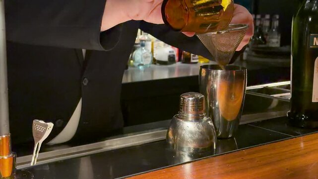 Professional Bartender in Suit Straining Mixed Drink at Japanese Bar