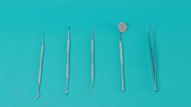 Top View Of Dentist Hands In Medical Gloves Collecting Steel Examination Tools From Organized Row Layout On Blue Background