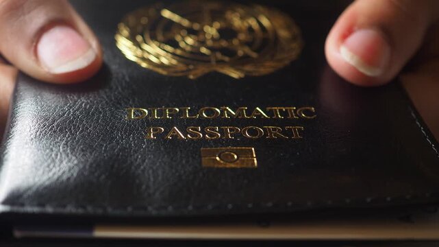 Holding a diplomatic passport in hand at a desk