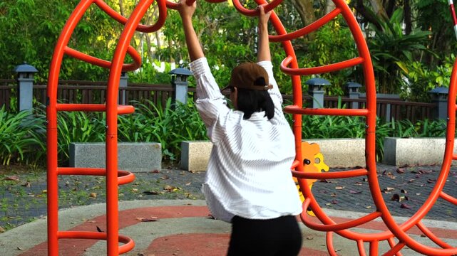 Woman Playing on Outdoor Monkey Bars in Park