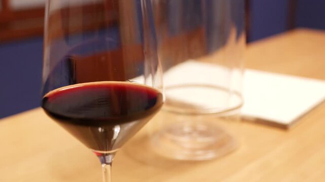 Close Up of Red Wine Glass on Restaurant Table with Bottle Being Removed
