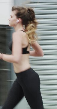 Running, fitness and woman in city with earphones for exercise, cardio workout and training. Runner, sports and person with active hobby for wellness, health and endurance with music, audio and track