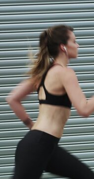 Running, exercise and woman in city with earphones for fitness, cardio workout and training. Runner, sports and person with active hobby for wellness, health and endurance with music, audio and track