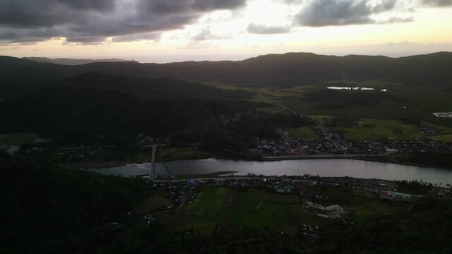 Scenic aerial dolly of Bato, Catanduanes with river landscape, mountain terrain, rural communities, and dramatic sunrise sky