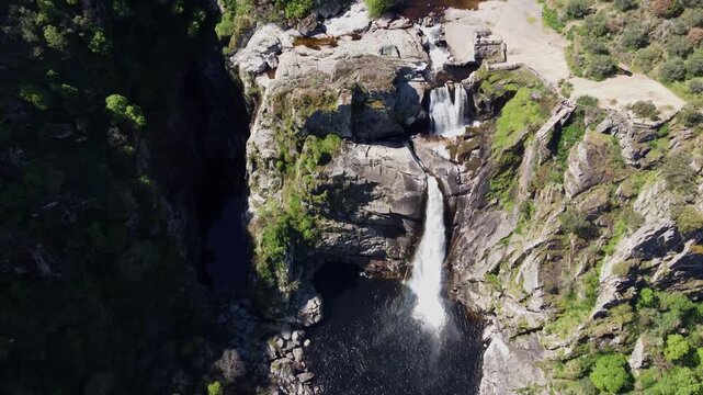 4K aerial drone view of the majestic Pozo de los Humos double waterfall in Salamanca, Spain. Powerful high-volume water flow plunging into the rocky canyon surrounded by lush green vegetation on a bri