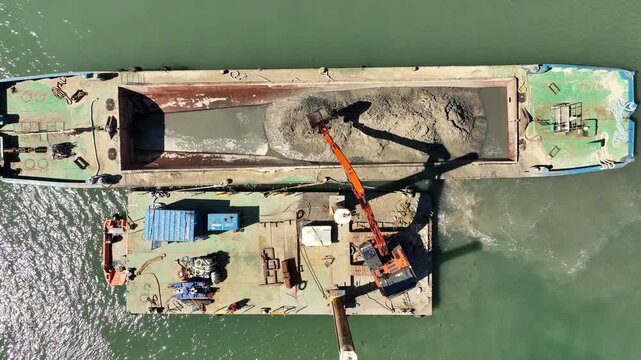 Sand dredging with digger and barge at portrush harbour northern ireland - drone view