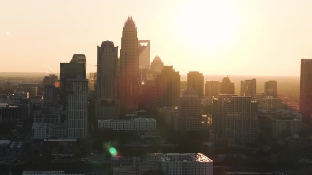 A 4k drone shot tracking around Charlotte, North Carolina at sunset with the golden beams of sunlight streaking through the skyscrapers