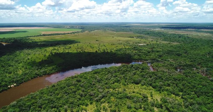 Meandering cerrado river crossing gallery forest and wet cattle pasture near Arinos, Minas Gerais, Brazil within the S&atilde;o Francisco basin and Urucuia Plateau agricultural frontier. Drone forward flyove