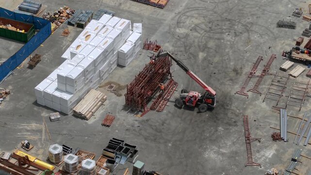 Aerial view of a telehandler moving metal frames near stacks of building materials at a Walmart construction site in World Golf Village, Florida, United States.