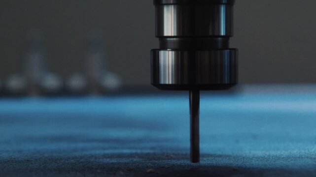 Close frontal macro of a CNC bit hovering over a board before the cutting process begins.