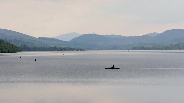 A canoe being paddled across Bala Lake or Llyn Tegid on a still Spring evening. Snowdonia National Park. Gwynedd. Wales.