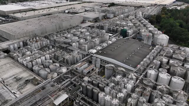 Gallo Winery in Modesto California with massive industrial fermentation tanks and production facilities at world's largest family-owned winery. Aerial drone flyover shot. Industrial district of town.