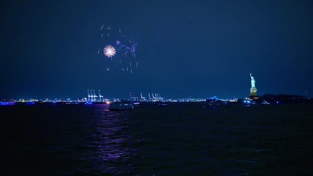 Fireworks exploding over New York harbor with Statue of Liberty. Night view of pyrotechnics above Upper New York Bay featuring the Statue of Liberty and port cranes.