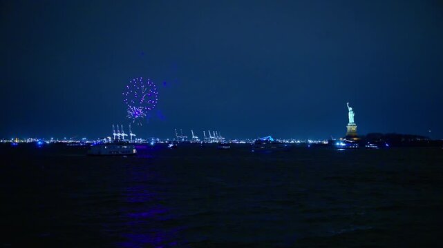 Purple fireworks over Statue of Liberty at night. Purple fireworks exploding in the night sky over the Statue of Liberty in New York City harbor.