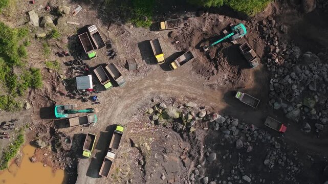 Aerial view of excavators and dump trucks operating at Tambang Pasir Merapi Kali Gendol Sand Mine, Cangkringan, Daerah Istimewa Yogyakarta, Indonesia.