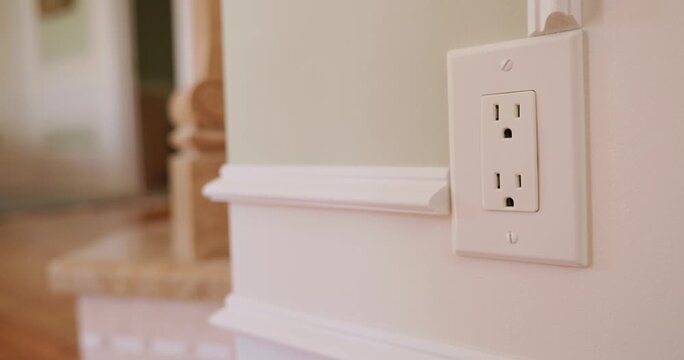 Hand unplugging electrical cord from wall outlet for safety or power saving.