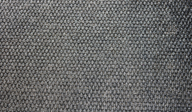 Dense texture of a dark grey loop pile carpet. The surface is composed of tightly woven, uniform yarn loops that create a pebbled, highly textured pattern.