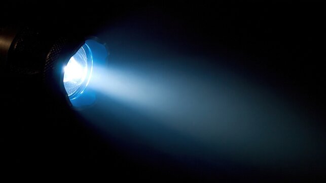 Bright beam of blue light from a projector lens illuminating the darkness for a cinematic experience