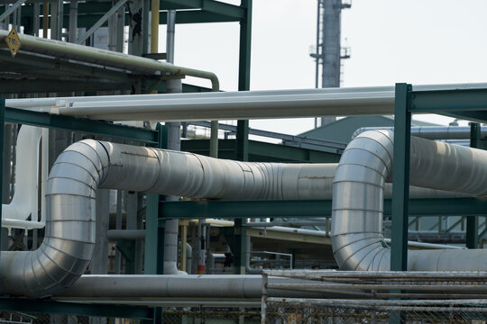 Refinery pipeline rack with insulated pipe bends supports petrochemical operation monitoring, maintenance planning, safety compliance audit, hazard control, energy infrastructure process inspection