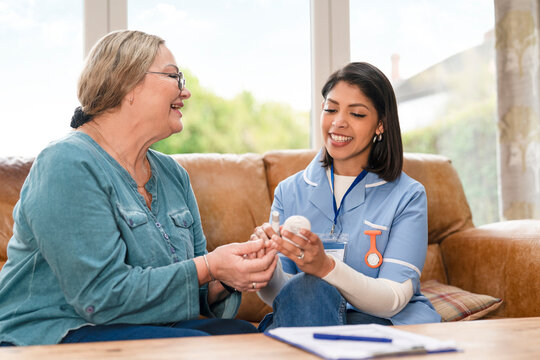 Senior woman receives care and advice from nurse during home visit in a sunny living room setting
