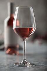 Obraz premium Elegant Glass of Refreshing Rosé Wine with Bottle Background for Celebrations and Relaxation
