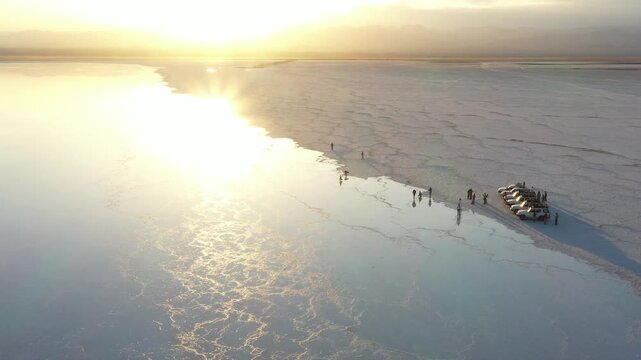 Aerial view of Danakil Desert with off-road vehicles and people on the salt flats at sunset in Dalol, Afar, Ethiopia.