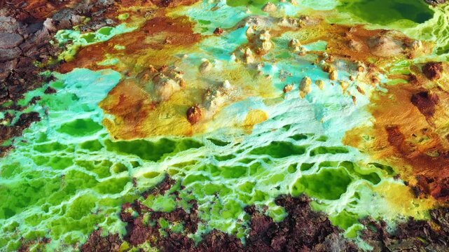 Aerial view of Danakil Desert featuring vibrant green sulfur pools and yellow salt formations in the volcanic landscape of Dalol, Afar, Ethiopia.